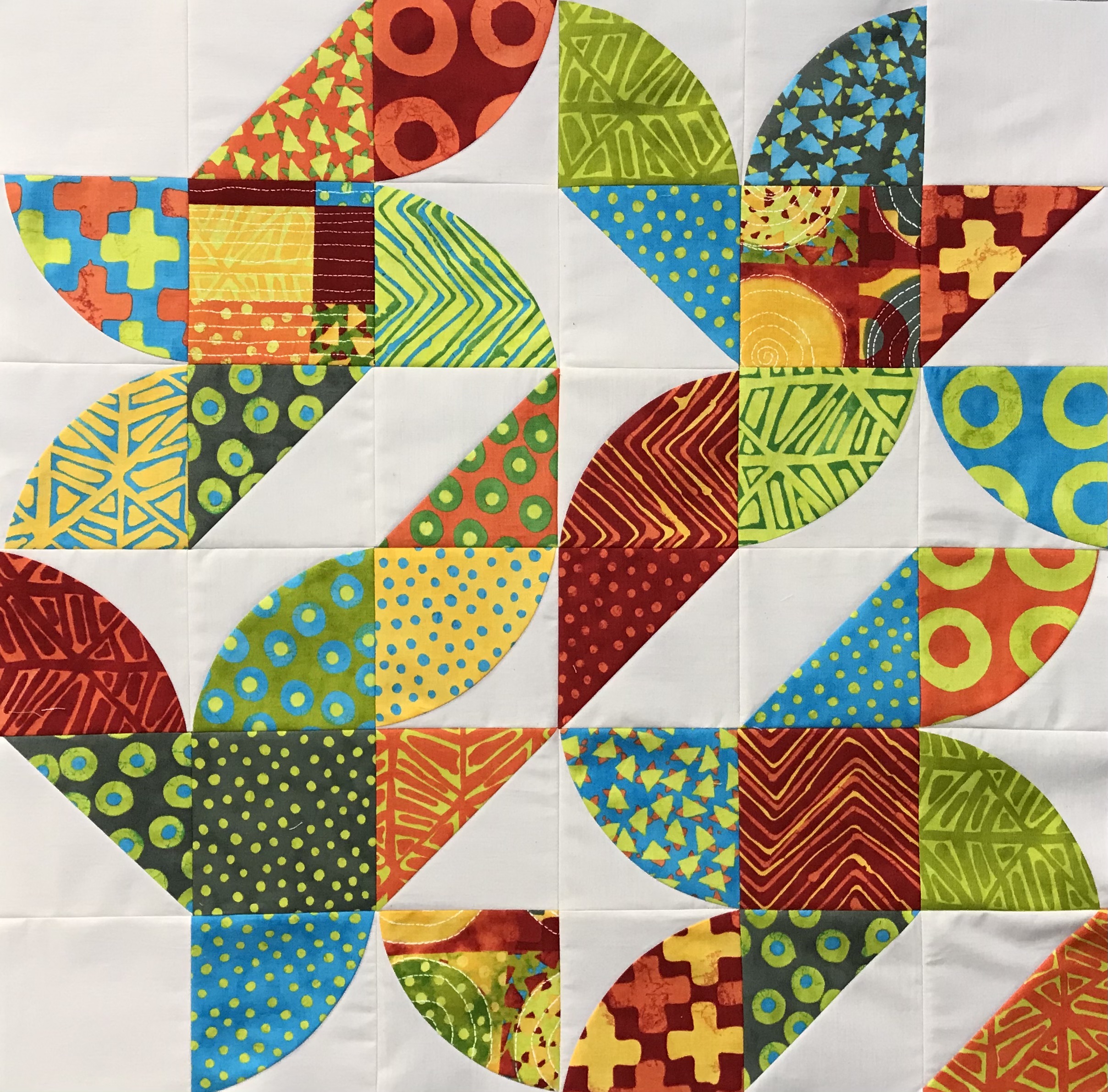 modern quilt with half square triangles and curved pieces, in bright and geometrically printed fabrics